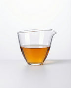 Clear glass fair cup with shu puerh tea liquid on a white background