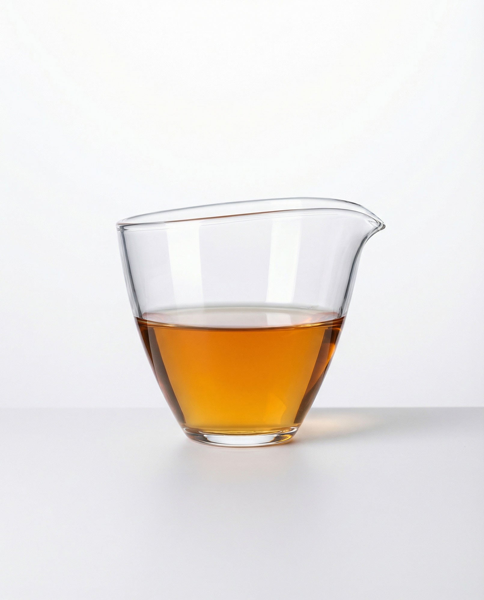 Clear glass fair cup with shu puerh tea liquid on a white background