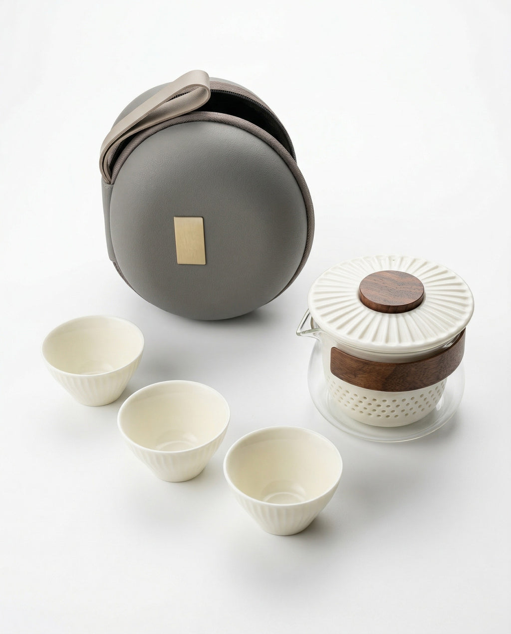 Travel compact tea set with ceramic cups, glass teapot, and round gray carrying case on a white background